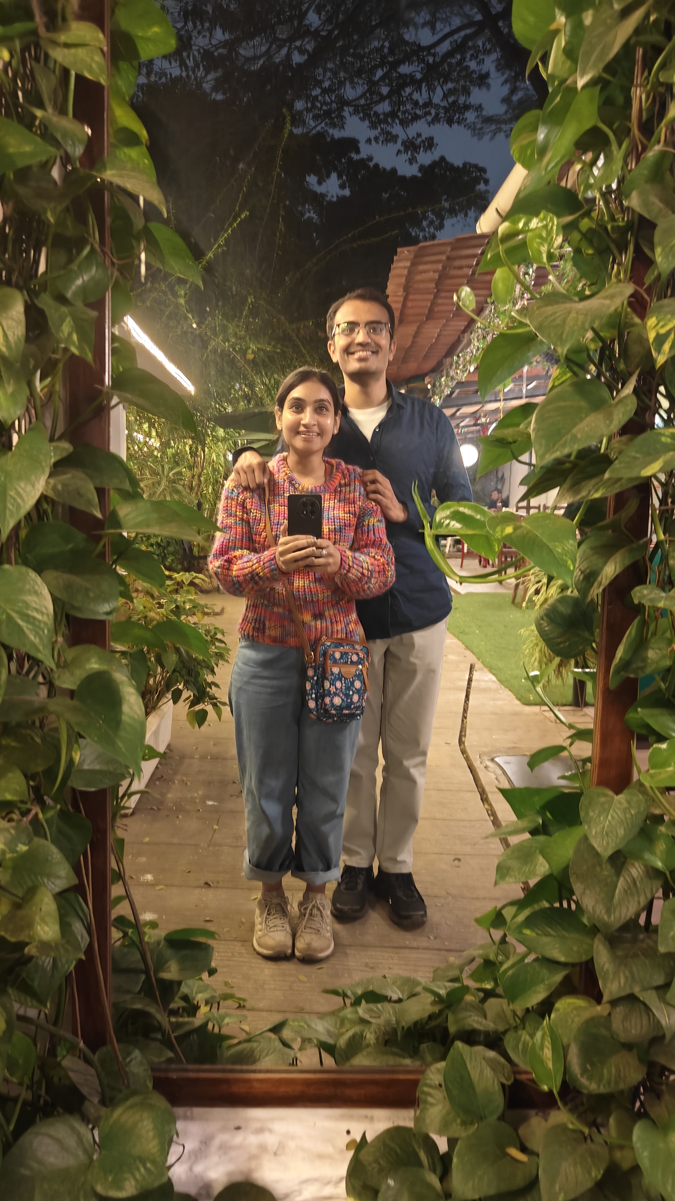 Sumi and Ajay mirror selfie framed by foliage